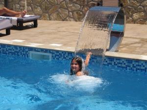 a woman in a swimming pool with a fountain at Guest House Villa Živanović in Herceg-Novi