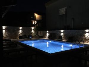 una piscina por la noche con luces encendidas en Guest House Villa Živanović, en Herceg-Novi