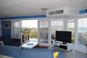 a living room with a blue couch and a television at Surfside On The Beach in Buddina