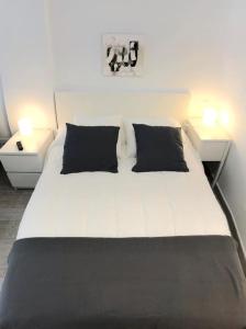 a white bed with two black pillows in a bedroom at 907 Estudio con terraza Puerto de la Cruz Martianez in Puerto de la Cruz