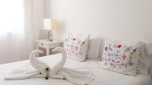 two swans towels on a bed with pillows at BLUE GUIDE Milfontes in Vila Nova de Milfontes