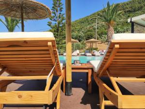 two chairs and an umbrella next to a pool at Panormos Beach Hotel Skopelos in Panormos Skopelos