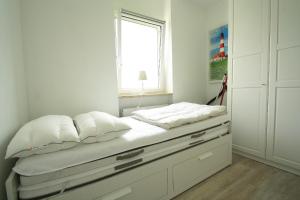 a bed with white pillows and a window in a room at Vier Jahreszeiten 1-58 in Großenbrode