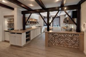 a large kitchen with white cabinets and wooden beams at Landhotel Esen in Neuharlingersiel