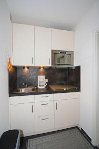 a kitchen with white cabinets and a sink at Vier Jahreszeiten 2-9 in Großenbrode