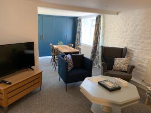 sala de estar con TV, mesa y sillas en The Croft Apartment, en Bourton on the Water