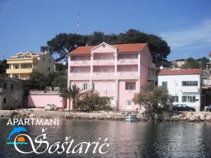 a pink building next to a body of water at Apartmani Sali Seaview in Sali
