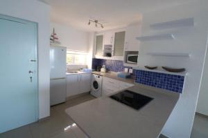 a kitchen with white cabinets and blue tiles on the wall at 74 Cascades in Durban
