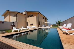 una piscina con sillas blancas y una casa en Villa Uluvud by Xenia Sicily Villas en Alcamo