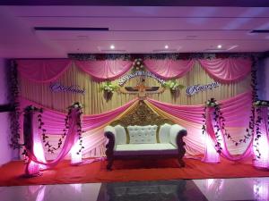 a stage with a bed in front of a pink curtain at Hotel Shahi Darbar in Navsāri