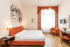 a bedroom with a bed and a desk and a chair at Hotel Johann Strauss in Vienna