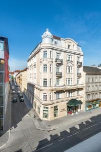 um grande edifício branco numa rua da cidade em Hotel Johann Strauss em Viena