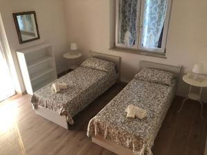 2 Betten in einem Zimmer mit 2 Tischen und einem Fenster in der Unterkunft Casa Magnolia in Pastrengo