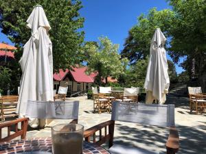 two tables with white umbrellas and chairs in a patio at Jubilee Hotel Troodos in Troodos