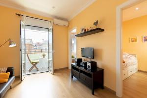 a bedroom with a bed and a tv and a balcony at Lodging Apartments Guell & Gracia in Barcelona