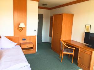 a hotel room with a bed and a desk with a television at Gasthof Pension Post in Denkendorf