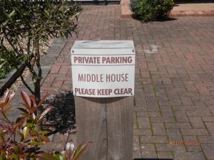 a sign on a wooden post with a private parking middle house at Middle House in Coventry