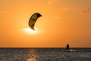 um homem a praticar kite surf no oceano ao pôr-do-sol em Beach House 9 em Scharendijke