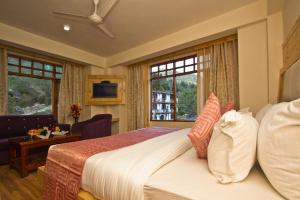 Hotel Hayer Regency في مانالي: غرفة فندقية بسرير واريكة ونوافذ