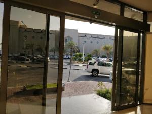 uma janela com vista para um parque de estacionamento com uma carrinha branca em Tanal Serviced Apartments em Al Khobar