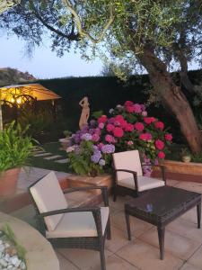 eine Terrasse mit 2 Stühlen, einem Tisch und Blumen in der Unterkunft Villa Degli Ulivi in Santa Maria del Cedro