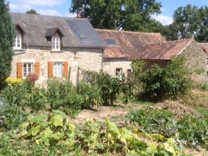 una antigua casa de piedra con un jardín delante de ella en La Grange Ô Belles en Champfrémont