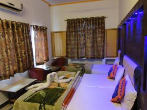 a room with two beds and chairs and curtains at Hotel Taj Plaza, VIP Road, Agra in Agra