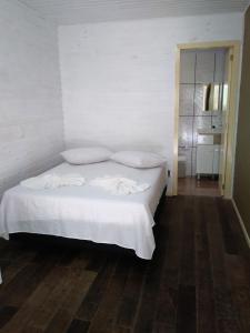 uma cama com lençóis brancos e almofadas num quarto em Chalé da Tranquilidade em Gramado