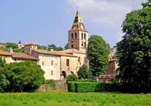 un vieux bâtiment avec une tour et une église dans l'établissement Gîte le Fort, à Vesseaux