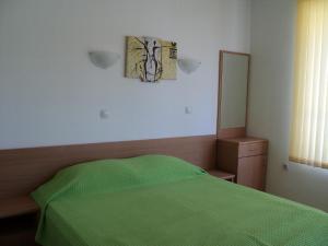 1 dormitorio con cama verde y espejo en Meni Apartments and Guest Rooms, en Sozopol
