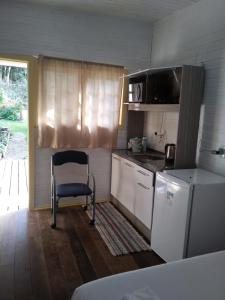 uma pequena cozinha com uma cadeira e um frigorífico em Chalé da Tranquilidade em Gramado