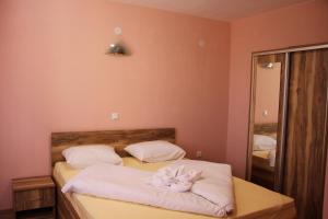 a bedroom with a bed with white sheets and a mirror at Хотел АЛЕКСАНДЪР in Pavel Banya