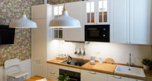 una cucina con armadi bianchi, lavandino e due pendant light di Flowers Apartment ALTIDO 25 a Como