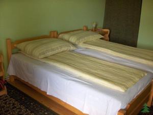 a wooden bed with two pillows on top of it at Pensiunea Fenyő in Corund