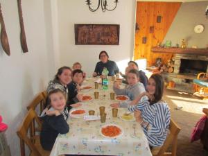 een groep kinderen die aan een tafel pizza eten bij Grande casa di famiglia in Temù