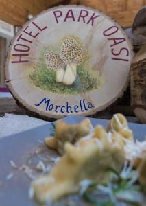 a table with a plate of food and a wooden sign at Hotel Park Oasi in Arta Terme