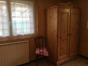 Habitación con armario de madera, silla y ventanas. en La Tannerie en Le Bourg-dʼOisans