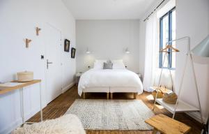 a white bedroom with a bed and a window at L’Ostréale in La Tremblade