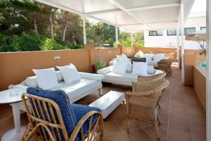 un patio con sofás, mesas y sillas en Hotel & Spa Entre Pinos-Adults Only en Es Caló
