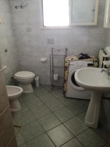 een badkamer met een toilet, een wastafel en een wasmachine bij La casa di Anna in Torre Lapillo