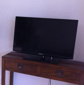 telewizor z płaskim ekranem siedzący na drewnianym stole w obiekcie Villa de vacances au calme proche de la mer w mieście La Londe-les-Maures