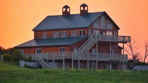 a large house on a hill with a sunset in the background at ReWild Ranch LLC in Sargent