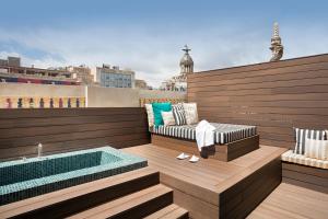 a rooftop patio with a hot tub and a bench at Praktik Èssens in Barcelona