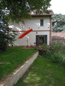 un paraguas rojo en el patio de una casa en Le Chais, en Villemur-sur-Tarn