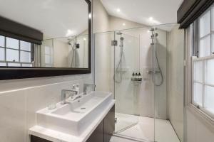 a white bathroom with a sink and a shower at Spectacular Knightsbridge House Harrods 1 minute in London