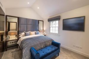 a bedroom with a large bed and a blue chair at Spectacular Knightsbridge House Harrods 1 minute in London