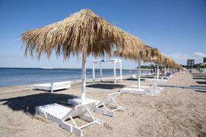 a group of chairs and a straw umbrella on a beach at Studio for 2 in Mamaia Summerland in Mamaia