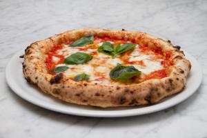 a pizza on a white plate on a table at Villa Sacro Cuore in San Giovanni Rotondo