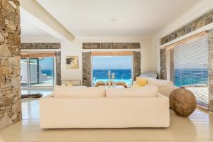 een woonkamer met een witte bank en een stenen muur bij Villa Coventina, Ornos - Cavo Delos, Mykonos in Agios Ioannis Mykonos +40 foto's