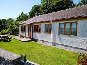 a white building with windows and a picnic table at Llinos Cottage in Beaumaris